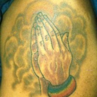 el tatuaje de las manos orantes en el humo con un arcoiris hecho en color