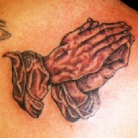 el tatuaje realista de las manos orantes