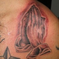 Manos rezando tatuaje en tina roja
