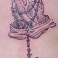 el tatuaje detallado con maos orantes y un rosario
