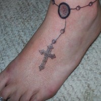 Tatuaje descolorido en el pie, pulsera con un cruz