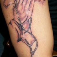 el tatuaje de las manos orantes con una cruz en el fondo