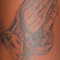 el tatuaje de tinta negra con manos orantes y un rosario