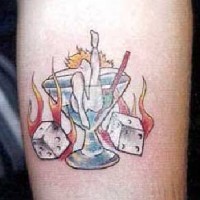 el tatuaje pin up de una chica en una copa y los dados quemandose en el fuego a los lados