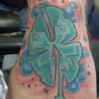 Tattoo von grüner Qualle,die einem Kleeblat ähnlich ist,  mit Bläschen an der Hand