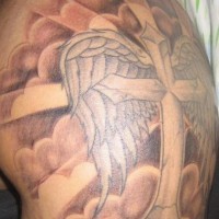Tatuaggio grande colorato sul deltoide  la croce con le ali tra le nuvole