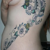 Un longue tatouage de flanc avec beaucoup de fleurs gouttes et entrelacs