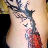 Tatuaggio sul fianco l'albero senza vita con le radici che escono da cuore
