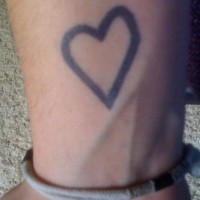 Black ink heart symbol tattoo on wrist