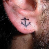 Kleiner schwarzer Anker Tattoo am Ohrläppchen