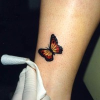 piccola farfalla colorata sulla gamba tatuaggio
