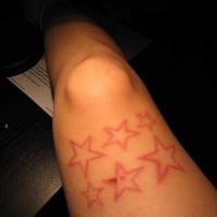 Tatuaje en tinta roja estrellas en la pierna