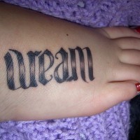 La rêve une inscription stylisée tatouage sur le pied