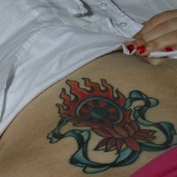 Bauch Tattoo mit stilisiertem blauem Rad in Flammen