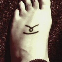 Symbole sur le pied,  tatouage en encre noire