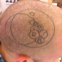 Tattoo von kleinen Kreisen mit Buchstaben innerhalb von  zwei großen Kreisen auf dem Kopf