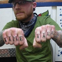Tattooed knuckles, time tide, big colourful inscription