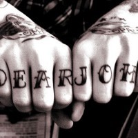 Cher John tatouage sur les phalanges aux lettres avec des ombres