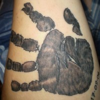 Black ink tattoo of child handprint