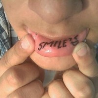 Tattoo on lip, black inscription smile sign smile