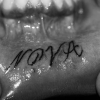 Tattoo on lip, nova, curled word inscription
