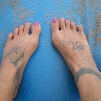 Tatuaggio in forma di braccialetto intorno alla caviglia e segni personali sui piedi