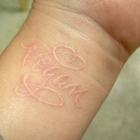 Tattoo in white ink with inscription vegan on wrist