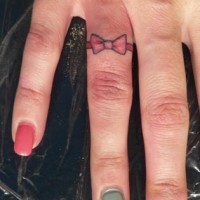 Tiny bow tattoo on finger