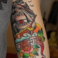 el tatuaje colorado de un barco en el mar y flores hecho en la mano