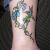 el tatuaje de colibri con flores azules hecho en color