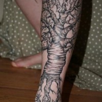 Un gros tatouage sur la jambe avec des arbres et des racines