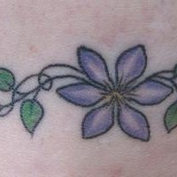 Tatuaggio colorato intorno della caviglia il fiore viola & la pianta