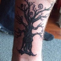el tatuaje de un arbol viejo hecho en tinta negra en la pierna