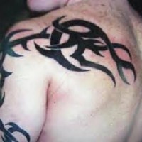 Gran tatuaje en el brazo y el omoplato estilo tribal