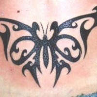 Bonito tatuaje de la mariposa tribal en el bajo de la espalda