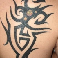 Black tribal sign tattoo on scapula