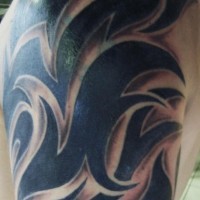 Masivo tatuaje tribal en tinta negra en el hombro