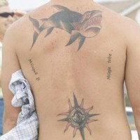 Tatuaje del tiburón maligno con unas inscripciones en la espalda
