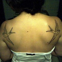 Le tatouage de haut du dos avec deux hirondelles volantes à côtés différentes