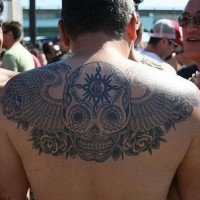 Verziertes Tattoo vom Schädel  mit Flügeln am oberen Rücken