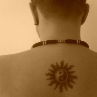 Yin-yang tattoo in black and white sun on upper back