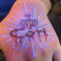 Le tatouage d’inscription avec une couronne à l'encre ultraviolette sur la main