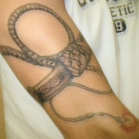 Tatuaje realista de un brazalete dando un latigazo.