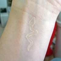 White ink tattoo with snake on wrist