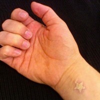 White ink wrist tattoo with small star