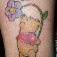 Le tatouage de Winnie l'ourson avec les fleurs et un papillon
