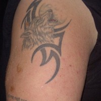 Tattoo with wolf howling on the moon and tribal sign