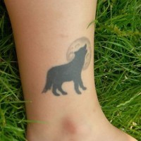 Tattoo mit schwarzem Wolf und Mond am Bein