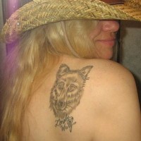 Tattoo mit Wolfskopf und Unterschrift am Schulterblatt