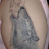 Tattoo mit silberfarbigem Wolf an der Schulter